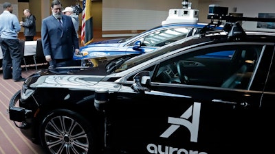 Pittsburgh Mayor William Peduto, left, checks out autonomous vehicles designed by Aurora Innovations, front, and Argo AI, rear, after signing an executive order outlining objectives and expectations for the safe testing and development of autonomous vehicles in Pittsburgh, Monday, March 4, 2019.