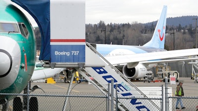 In this photo taken Monday, March 11, 2019, a Boeing 737 MAX 8 airplane being built for TUI Group sits parked in the background at right at Boeing Co.'s Renton Assembly Plant in Renton, Wash. Britain, France and Germany on Tuesday joined a rapidly growing number of countries grounding the new Boeing plane involved in the Ethiopian Airlines disaster or turning it back from their airspace, while investigators in Ethiopia looked for parallels with a similar crash just five months ago.