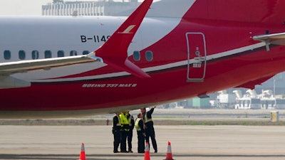 Ground crew chat near a Boeing 737 MAX 8 plane operated by Shanghai Airlines parked on tarmac at Hongqiao airport in Shanghai, China, Tuesday, March 12, 2019. U.S. aviation experts on Tuesday joined the investigation into the crash of an Ethiopian Airlines jetliner that killed 157 people, as a growing number of airlines grounded the new Boeing plane involved in the crash.