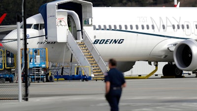 In this March 14, 2019, file photo a worker walks next to a Boeing 737 MAX 8 airplane parked at Boeing Field in Seattle. U.S. prosecutors are looking into the development of Boeing's 737 Max jets, a person briefed on the matter revealed Monday, the same day French aviation investigators concluded there were 'clear similarities' in the crash of an Ethiopian Airlines Max 8 last week and a Lion Air jet in October.