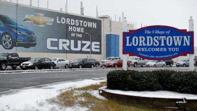 In this Nov. 27, 2018, file photo, a banner depicting the Chevrolet Cruze model vehicle is displayed at the General Motors' Lordstown plant, in Lordstown, Ohio. GM employees in Lordstown and other factories in Michigan and Maryland that are targeted to close within a year say moving will force them to leave behind relatives, even their children, in some cases.