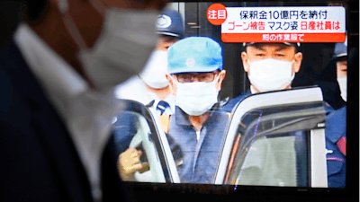 A man walks by a TV monitor which reports on former chairman of Nissan Motor Co., Carlos Ghosn, in Tokyo Wednesday, March 6, 2019. Disguised as a construction worker, Ghosn left a Tokyo detention center Wednesday after posting 1 billion yen ($8.9 million) bail.