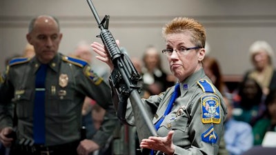 In this Jan. 28, 2013, file photo, firearms training unit Detective Barbara J. Mattson, of the Connecticut State Police, holds a Bushmaster AR-15 rifle, the same make and model used by Adam Lanza in the 2012 Sandy Hook School shooting, during a hearing at the Legislative Office Building in Hartford, Conn. A divided Connecticut Supreme Court ruled, Thursday, March 14, 2019, gun maker Remington can be sued over how it marketed the Bushmaster rifle used in the massacre.