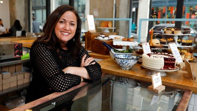 In this Wednesday, Feb. 6, 2019 photo, Dawn Casale, founder of One Girl Cookies, poses for photos in her shop in the Dumbo neighborhood of the Brooklyn borough of New York. Mayor Bill de Blasio wants New York to become the first place in the 50 states to make private businesses provide time off with pay. Employees at Casale's bakery get paid time off after five years, or if they're managers; others can arrange unpaid vacation, she said. 'I would love to be able to provide vacation time to my employees ... but the reality of it is not whether or not we want to give it — it's whether we can give it,' said Casale.