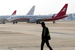 A ground crew walks near a Boeing 737 Max 8 plane operated by Shanghai Airlines parked on the tarmac at Hongqiao airport in Shanghai, China, Tuesday, March 12, 2019. U.S. aviation experts on Tuesday joined the investigation into the crash of an Ethiopian Airlines jetliner that killed 157 people, as a growing number of airlines grounded the new Boeing plane involved in the crash.