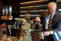 In this March 5, 2019, photo Kevin Johnson, right, CEO of Starbucks, makes coffee using a siphon method alongside barista Dylan George, left, as Johnson visits the company's Starbucks Reserve store in the company's headquarters building in Seattle's SODO neighborhood.
