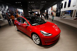In this Feb. 9, 2019, file photograph, buyers look over a Model 3 in a Tesla store in Cherry Creek Mall in Denver. Tesla is shifting all of its sales from stores to the internet, saying the move is needed to cut costs so it can sell the mass-market Model 3 for a starting price of $35,000. The Palo Alto, California, company announced the change Thursday, Feb. 28.