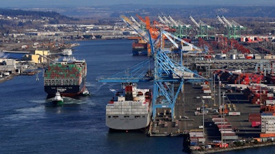 In this Tuesday, March 5, 2019, file photo the Cape Kortia container ship, left, heads into the Port of Tacoma in Commencement Bay in Tacoma, Wash. The U.S. trade deficit jumped nearly 19 percent in December, pushing the trade imbalance for all of 2018 to widen to a decade-long high of $621 billion. The gap with China on goods widened to an all-time record of $419.2 billion.