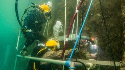 US Navy construction divers weld zinc anodes onto underwater piers at Naval Base Guam in 2017. The Navy has invented a new anode alloy that is zinc-free and cost-effective.