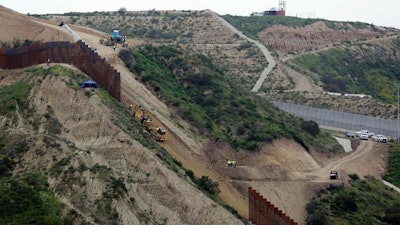 In this March 11, 2019 photo, construction crews replace a section of the primary wall separating San Diego, above right, and Tijuana, Mexico, below left, seen from Tijuana, Mexico. The Pentagon has sent a 20-page list of military construction projects to lawmakers who want to know which might be cut to pay for President Donald Trump’s wall along the border with Mexico. Democrats say the list shows that Trump is willing to cut needed defense spending and make the U.S. less secure, just to finance his wall. Trump has vetoed legislation aimed at blocking the cuts, and a veto override vote is set for next week.