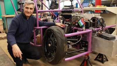 Prof. Amir Khajepour stands next to a vehicle containing his new wheel unit.