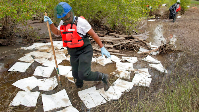 This July 11, 2011, file photo, shows an oil spill crew worker for Oil Mop Emergency Response stepping out of a ring of absorbent pads along a flood plain of the Yellowstone River where oil was found collected, near Laurel, Mont. Exxon Mobil Corp. has agreed to pay a $1.05 million penalty to settle alleged federal water pollution violations resulting from a 2011 oil pipeline spill into Montana's Yellowstone River.
