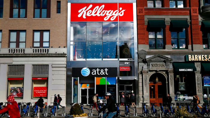 In this Dec. 14, 2017, file photo people bike and walk by Kellogg's NYC Cafe at Union Square in New York. Kellogg is selling its iconic Keebler cookie brand and other sweet snacks businesses to Ferrero for $1.3 billion.