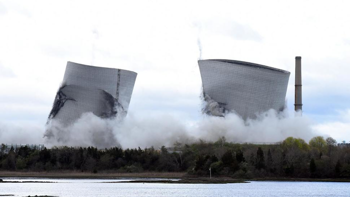 The two 500-foot cooling towers of the former Brayton Point Station collapse after explosive charges are detonated in Somerset, Mass., on Saturday, April 27, 2019. The plant had burned coal since 1963. By the time it stopped producing power in 2017, it was the last coal-fired plant in Massachusetts.