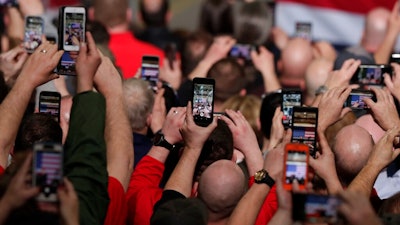 In this March 20, 2019, photo workers take photos with their phones as President Donald Trump speaks at Joint Systems Manufacturing Center in Lima, Ohio. Congress is starting to show interest in prying open the “black box” of tech companies’ artificial intelligence much the same way the federal government checks under car hoods and audits banks. President Donald Trump’s administration is also taking notice and has made the development of “trustworthy” algorithms a part of the White House’s new AI initiative.