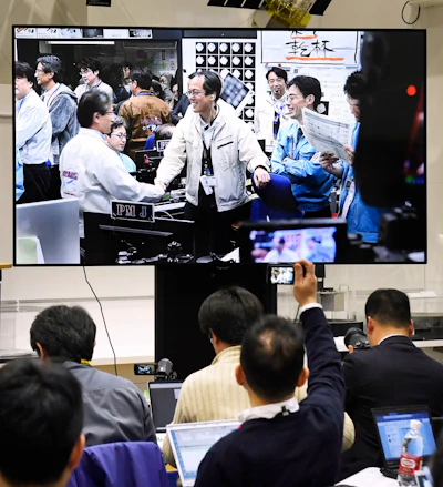 Members of The Japan Aerospace Exploration Agency, or JAXA, seen on screen, celebrate, as Hayabusa2 spacecraft safely evacuated and remained intact after the blast, in Sagamihara, near Tokyo, Friday, April 5, 2019. Japan's space agency says its spacecraft has released an explosive onto an asteroid to make a crater on its surface and collect underground samples to find possible clues to the origin of the solar system.