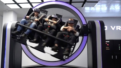 In this April 2, 2019, photo, Liu Zixing, a mining ore businessman, right, rides a virtual reality 'gyroscope' in a VR theme park in Nanchang, China. One of the largest virtual reality theme parks in the world has opened its doors in southwestern China, sporting 42 rides and exhibits from VR bumper cars to VR shoot-em-ups. It's part of an effort by Beijing to get ordinary people excited about the technology - part of a long-term bet that VR will come into widespread use.