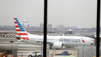 In a March 13, 2019 file photo, an American Airlines Boeing 737 MAX 8 sits at a boarding gate at LaGuardia Airport in New York. American Airlines said Sunday, April 7, 2019 it is extending by over a month its cancellations of about 90 daily flights as the troubled 737 Max plane remains grounded by regulators. The Boeing-made Max jets have been grounded in the U.S. and elsewhere since mid-March, following two deadly crashes in Ethiopia and Indonesia.