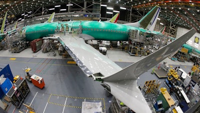 In this March 27, 2019, file photo taken with a fish-eye lens, a Boeing 737 MAX 8 airplane sits on the assembly line during a brief media tour in Boeing's 737 assembly facility in Renton, Wash. Boeing is cutting production of its grounded Max airliner this month to focus on fixing flight-control software and getting the planes back in the air. The company said Friday, April 5, that starting in mid-April it will cut production of the 737 Max from 52 to 42 planes per month.