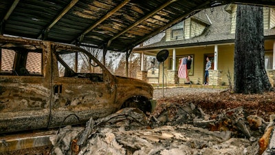In this March 19, 2019, Sean and Dawn Herr collect an American flag that survived the Camp Fire along with their Paradise, Calif., home. The Herrs' home, built in 2010, was scorched and had smoke damage inside so the family is living indefinitely in nearby Chico. The Herrs credit the home’s survival to strict building codes and to gravel that encircled the building and kept the flames back.