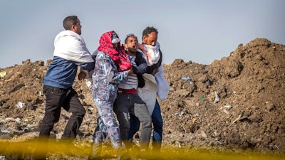 In this Wednesday March 13, 2019 file photo, a grieving relative who lost his wife in the plane crash is helped by a member of security forces and others near Bishoftu, in Ethiopia, at the scene where the Ethiopian Airlines jet crashed just after taking off from Addis Ababa on March 10, killing all 157 on board. A preliminary report finds that the crew of the Ethiopian Airlines jet that crashed last month performed all the procedures recommended by Boeing but could not control the plane.