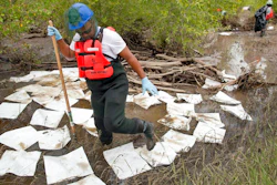 This July 11, 2011, file photo, shows an oil spill crew worker for Oil Mop Emergency Response stepping out of a ring of absorbent pads along a flood plain of the Yellowstone River where oil was found collected, near Laurel, Mont. Exxon Mobil Corp. has agreed to pay a $1.05 million penalty to settle alleged federal water pollution violations resulting from a 2011 oil pipeline spill into Montana's Yellowstone River.
