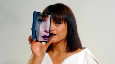 A model holds a Samsung Galaxy Fold smartphone to her face, during a media preview event in London, Tuesday April 16, 2019. Samsung is hoping the innovation of smartphones with folding screens giving a large interactive space or smaller usual screen, reinvigorates the market.