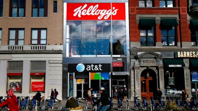 In this Dec. 14, 2017, file photo people bike and walk by Kellogg's NYC Cafe at Union Square in New York. Kellogg is selling its iconic Keebler cookie brand and other sweet snacks businesses to Ferrero for $1.3 billion.