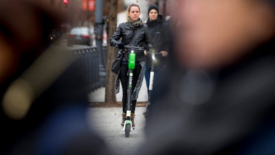 In this Dec. 4, 2018, photo a couple rides scooters near the White House in Washington. Electric scooters are overtaking station-based bicycles as the most popular form of shared transportation outside transit and cars.