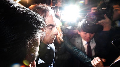 In this April 3, 2019, photo, former Nissan Chairman Carlos Ghosn, center, mobbed by journalists leaves his lawyer's office in Tokyo. Japanese prosecutors took Ghosn for questioning Thursday, April 4, 2019, barely a month after he was released on bail ahead of his trial on financial misconduct charges.