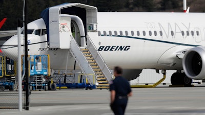 In this March 14, 2019, file photo, a worker walks next to a Boeing 737 MAX 8 airplane parked at Boeing Field in Seattle. U.S. aviation regulators said Monday, April 1, Boeing needs more time to finish changes in a flight-control system suspected of playing a role in two deadly crashes.