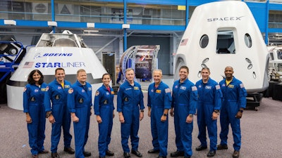 This undated photo made available by NASA on Aug. 3, 2018 shows mockups of Boeing's CST-100 Starliner and SpaceX's Crew Dragon capsules with crew members, from left, Sunita Williams, Josh Cassada, Eric Boe, Nicole Mann, Christopher Ferguson, Douglas Hurley, Robert Behnken, Michael Hopkins and Victor Glover at the Johnson Space Center in Texas. Boe, pulled for unspecified medical reasons in January 2019, was replaced by Mike Fincke. The Starliner capsule, supposed to make its debut in April 2019, was pushed back until August. SpaceX’s Dragon capsule could fly with a test crew in the summer of 2019, but the schedule is under review.