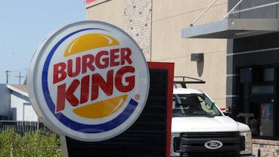 In this Thursday, April 25, 2019, photo a customer takes his order from the drive through window at a Burger King in Redwood City, Calif. Restaurant Brands International, the parent company of Burger King and Tim Hortons, reports financial results on Monday, April 29.