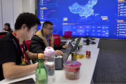 In this Nov. 11, 2018, file photo, workers use their laptops near a display showing sales data at the command center at the headquarters of an e-commerce retailer in Beijing. Remarks by the head of Chinese online business giant Alibaba that young people should work 12-hour days, six days a week if they want financial success have prompted a public debate over work-life balance in the country.