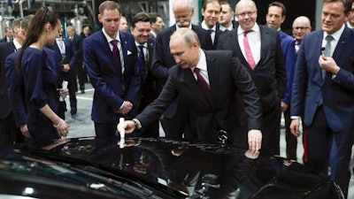 Russian President Vladimir Putin signs a car hood during an opening ceremony of the Mercedes Benz automobile assembly plant outside Moscow, Russia, Wednesday, April 3, 2019, with Chairman of the Board of Management of Daimler AG Dieter Zetsche, background centre, and German economics ministers Peter Altmaier, next right to Putin. Germany’s Daimler AG has opened a new Mercedes factory in Russia, part of a 250 million euro ($281 million) investment it says will create 1,000 jobs.