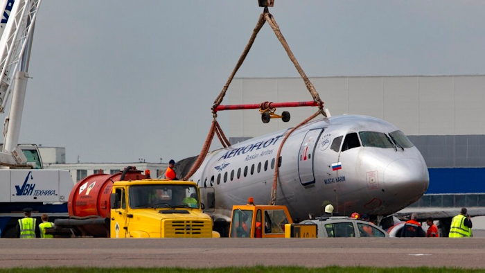 A crane lifts the damaged Sukhoi SSJ100 aircraft of Aeroflot Airlines in Sheremetyevo airport, outside Moscow, Russia, Monday, May 6, 2019. Russian emergency workers have recovered 41 bodies and two flight recorders from the wreckage of the plane that caught fire during an emergency landing in Moscow, officials said Monday as they sought to discover the cause of the disaster.