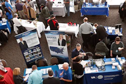 In this March 7, 2019, photo visitors to the Pittsburgh veterans job fair meet with recruiters at Heinz Field in Pittsburgh.