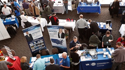 In this March 7, 2019, photo visitors to the Pittsburgh veterans job fair meet with recruiters at Heinz Field in Pittsburgh.