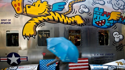 A woman walks by a bench painted with an American flag outside a fashion boutique selling U.S. brand clothing at the capital city's popular shopping mall in Beijing, Monday, May 13, 2019. Companies waited Monday to see how China decides to retaliate for President Donald Trump's latest tariff hike while forecasters warned their escalating fight over technology and trade might disrupt a Chinese economic recovery.