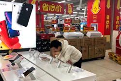 A man browses an iPhone unit on display at a section selling Apple's products together with Chinese made electric appliances at a hypermarket in Beijing, Thursday, May 9, 2019. Ratcheting up tension ahead of talks in Washington, China vowed Thursday to defend its own interests and retaliate if President Donald Trump goes ahead with more tariff hikes in a dispute over trade and technology.