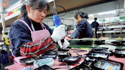 In this Saturday, March 30, 2019, file photo, workers assemble LED lights at a factory in Yushan county in central China's Jiangxi province. China is cutting taxes on its fledgling software and integrated circuit industries to spur development in the face of U.S. export controls that threaten to handicap Chinese tech companies.