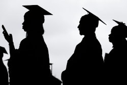 In this May 17, 2018, file photo, new graduates line up before the start of the Bergen Community College commencement at MetLife Stadium in East Rutherford, N.J. A college degree has long been a ticket to the U.S. middle class. Yet a new survey shows that college graduates aren’t as likely as they once were to feel they belong to the middle class.