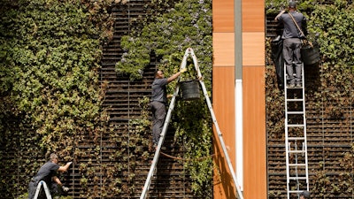 In this April 9, 2019, photo gardeners work on a vertical planters in Philadelphia. On Tuesday, April 30, the Labor Department releases the employment cost index for the first quarter, a measure of wage and benefit growth.