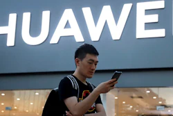 In this Monday, May 20, 2019, photo, a man uses his smartphone outside a Huawei store in Beijing. Chinese tech giant Huawei has filed a motion in U.S. court challenging the constitutionality of a law that limits its sales of telecom equipment.