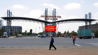 In this March 21, 2018 file photo, people walk past the gate of the Eastern Industrial Zone in Ethiopia in the town of Dukem near the capital, Addis Ababa. Ethiopian garment factory workers are now, on average, the lowest paid in any major garment-producing company worldwide, a new report said Tuesday, May 7, 2019.