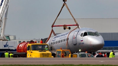 A crane lifts the damaged Sukhoi SSJ100 aircraft of Aeroflot Airlines in Sheremetyevo airport, outside Moscow, Russia, Monday, May 6, 2019. Russian emergency workers have recovered 41 bodies and two flight recorders from the wreckage of the plane that caught fire during an emergency landing in Moscow, officials said Monday as they sought to discover the cause of the disaster.