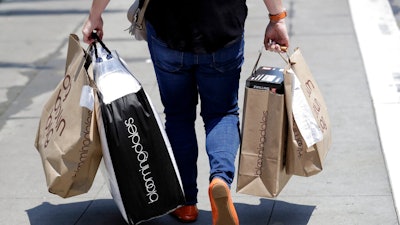 In this July 3, 2018, file photo, a shopper carries bags in San Francisco. American consumers are feeling more confident this April 2019, though optimism hasn’t fully recovered from a period of roiling markets and slowed hiring early this year. The Conference Board, a business research group, said Tuesday, April 30, 2019, that its consumer confidence index rose to 129.2 in April, from 124.2 in March.