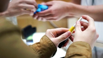 In this Oct. 22, 2018 file photo, visitors try out a pen-like 'heat-not-burn' device at an IQOS store at Ginza in Tokyo. On Tuesday, April 30, 2019, the U.S. Food and Drug Administration said it will allow Philip Morris International to sell the cigarette alternative that heats tobacco without burning it.