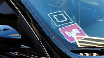 In this Jan. 12, 2016, file photo, a ride share car displays Lyft and Uber stickers on its front windshield in downtown Los Angeles. One in six Uber and Lyft drivers in the New York City and Seattle areas are driving vehicles with outstanding recalls, according to Consumer Reports. But taking a taxi or limousine isn’t necessarily a safer option as nearly a quarter of traditional for-hire vehicles in New York City also have outstanding recalls, Consumer Reports said.