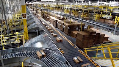 In this Aug. 3, 2017, file photo, packages ride on a conveyor system at an Amazon fulfillment center in Baltimore. Amazon, which is racing to deliver packages faster, is turning to its employees with a proposition: Quit your job and we’ll help you start a business delivering Amazon package. The offer, announced Monday, May 13, 2019, comes as Amazon seeks to speed up its shipping time from two days to one for its Prime members.
